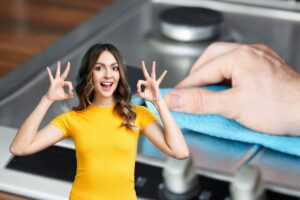 donna che fa ok e mano che pulisce piano cottura